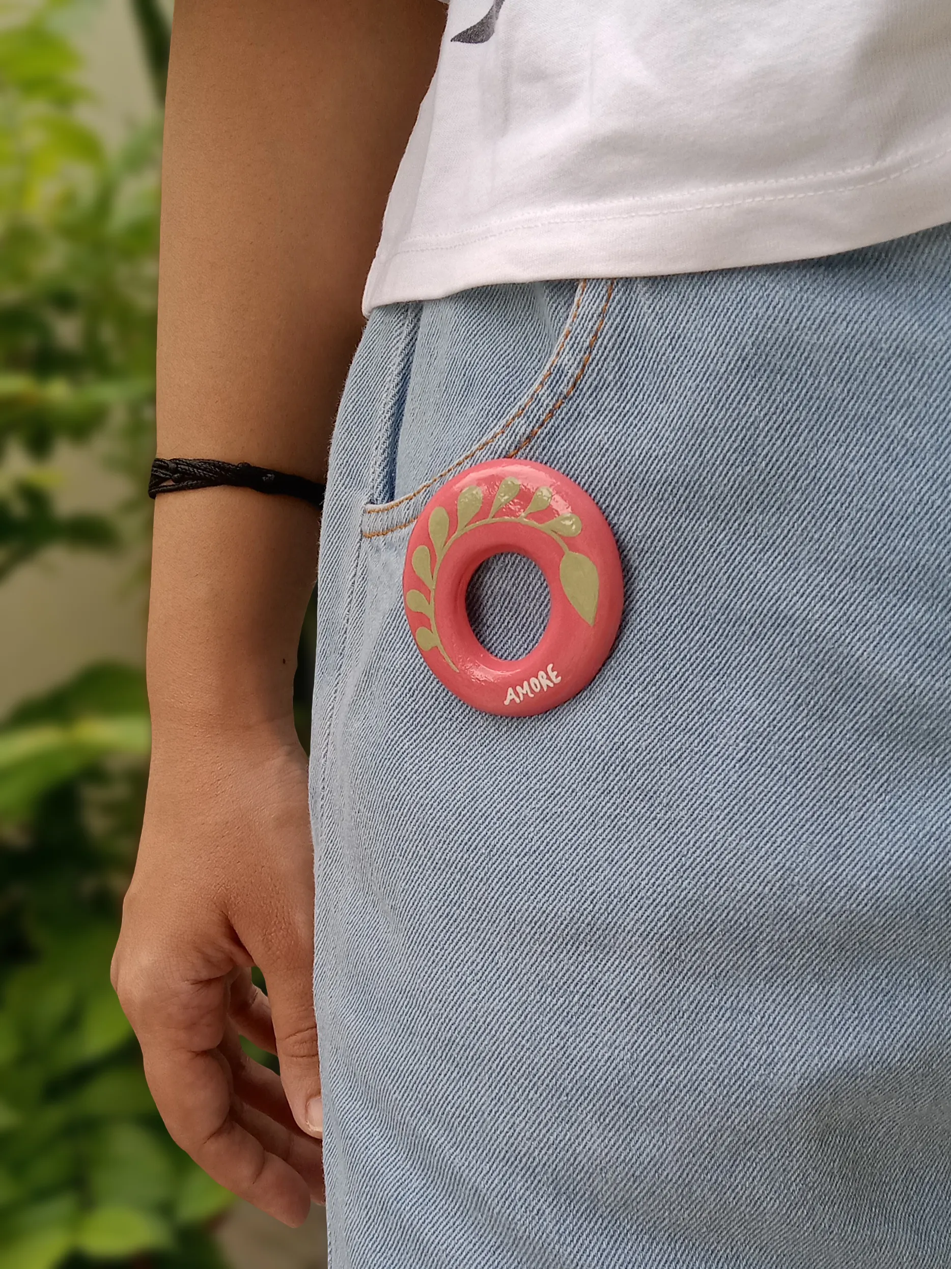 Studio Gayatri handmade oval pink clay sunglasses holder brooch featuring a hand-painted olive green botanical leaf design.