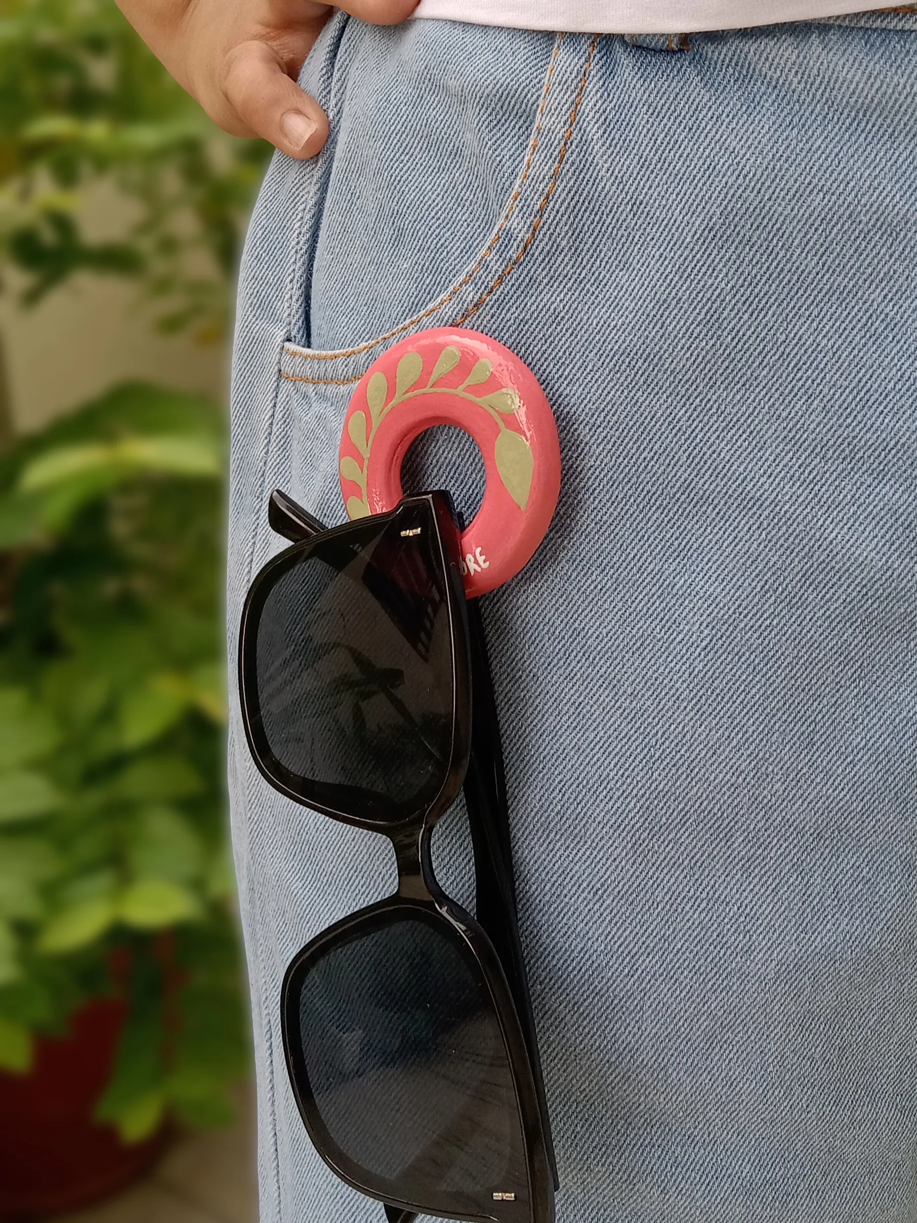 Oval clay brooch pin holding sun glasses while pinned to a denim jeans pocket