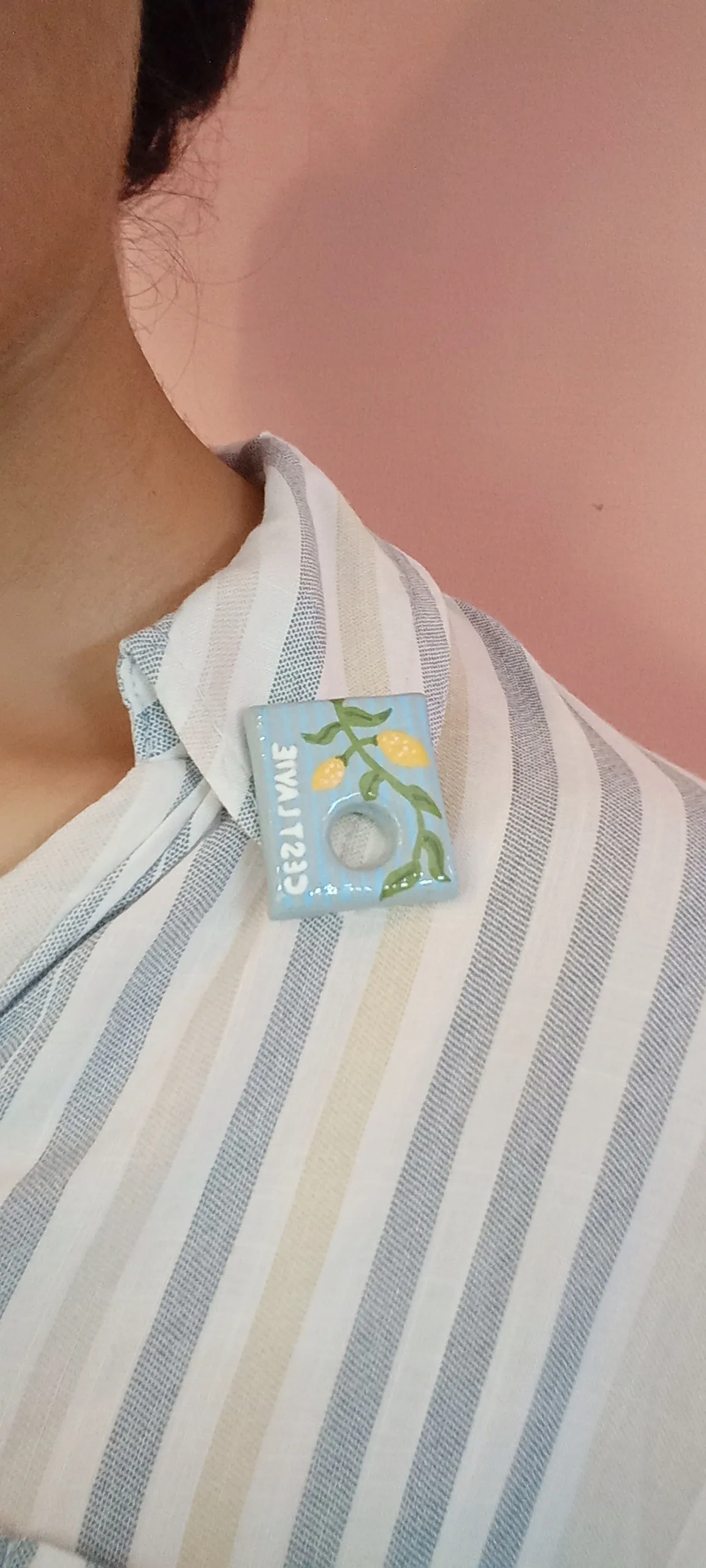 Clay glass holding brooch pinned on a cotton shirt