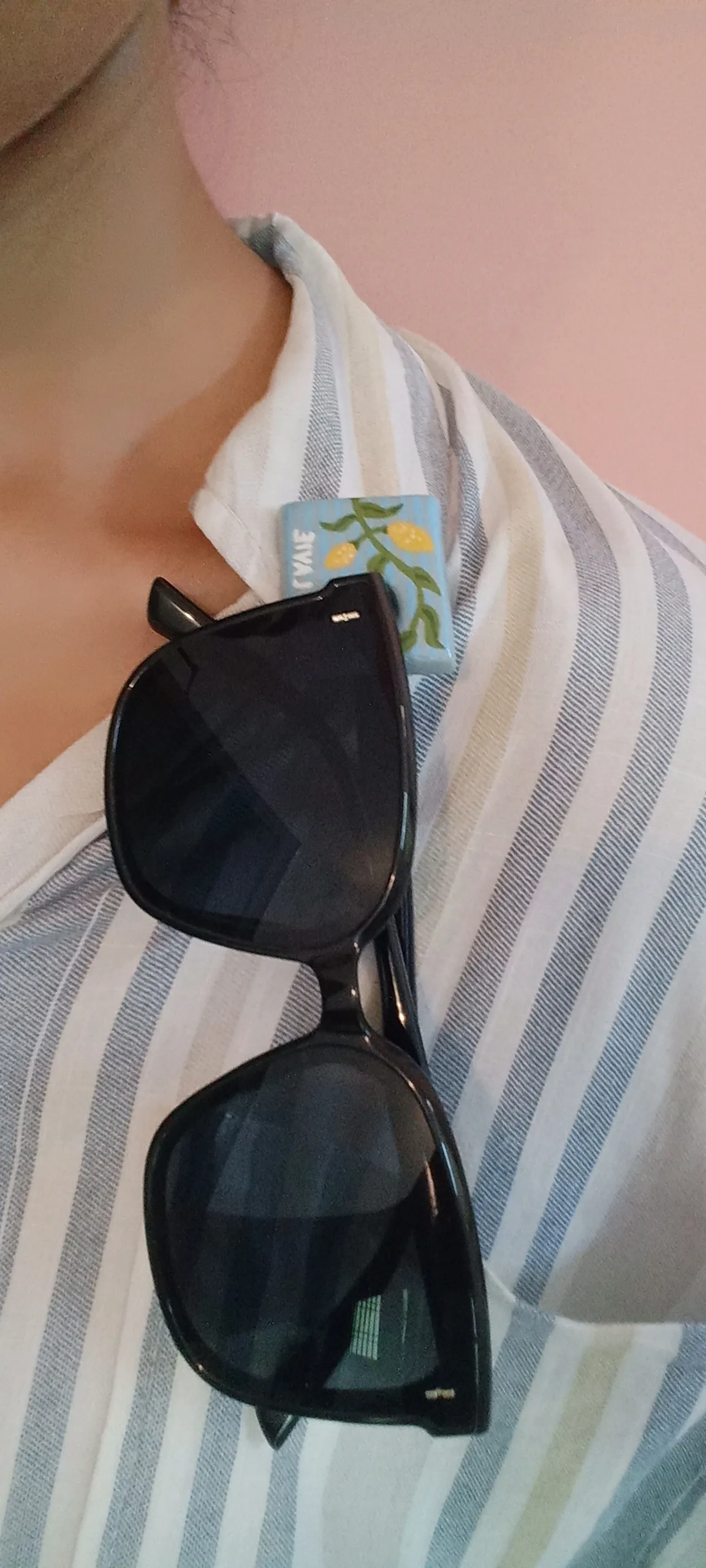 Clay brooch holding a pair of sunglasses while being pinned to a collar of a shirt.