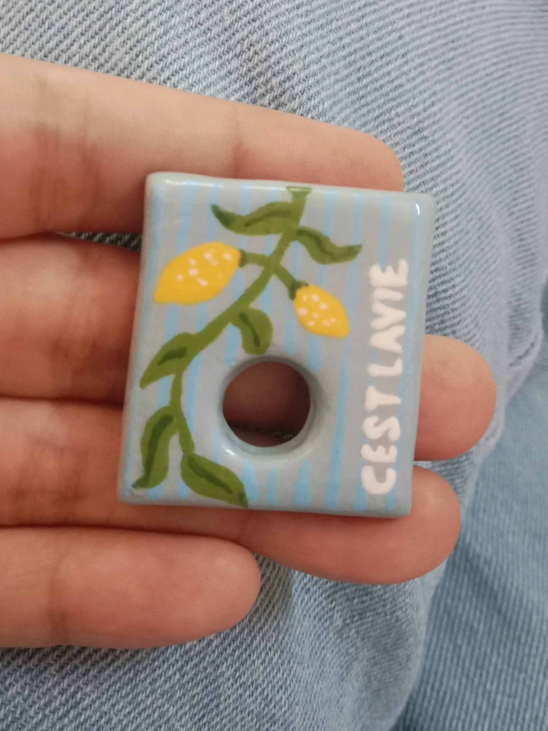 Front of a clay brooch with handpainted lemon branch and cest lavie inspiration