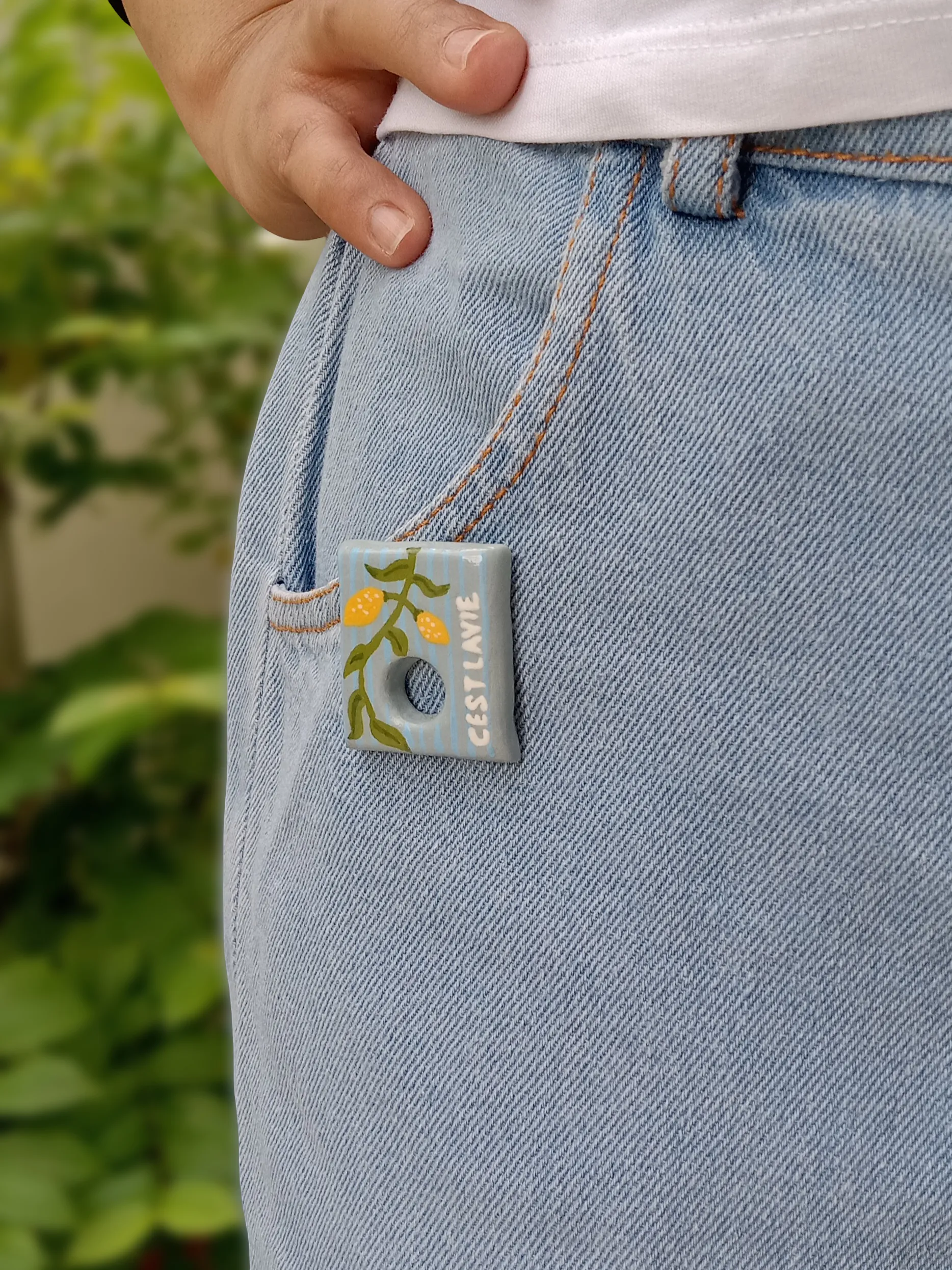 Studio Gayatri handmade botanical clay sunglasses holder brooch featuring a hand-painted blue and yellow lemon branch design.