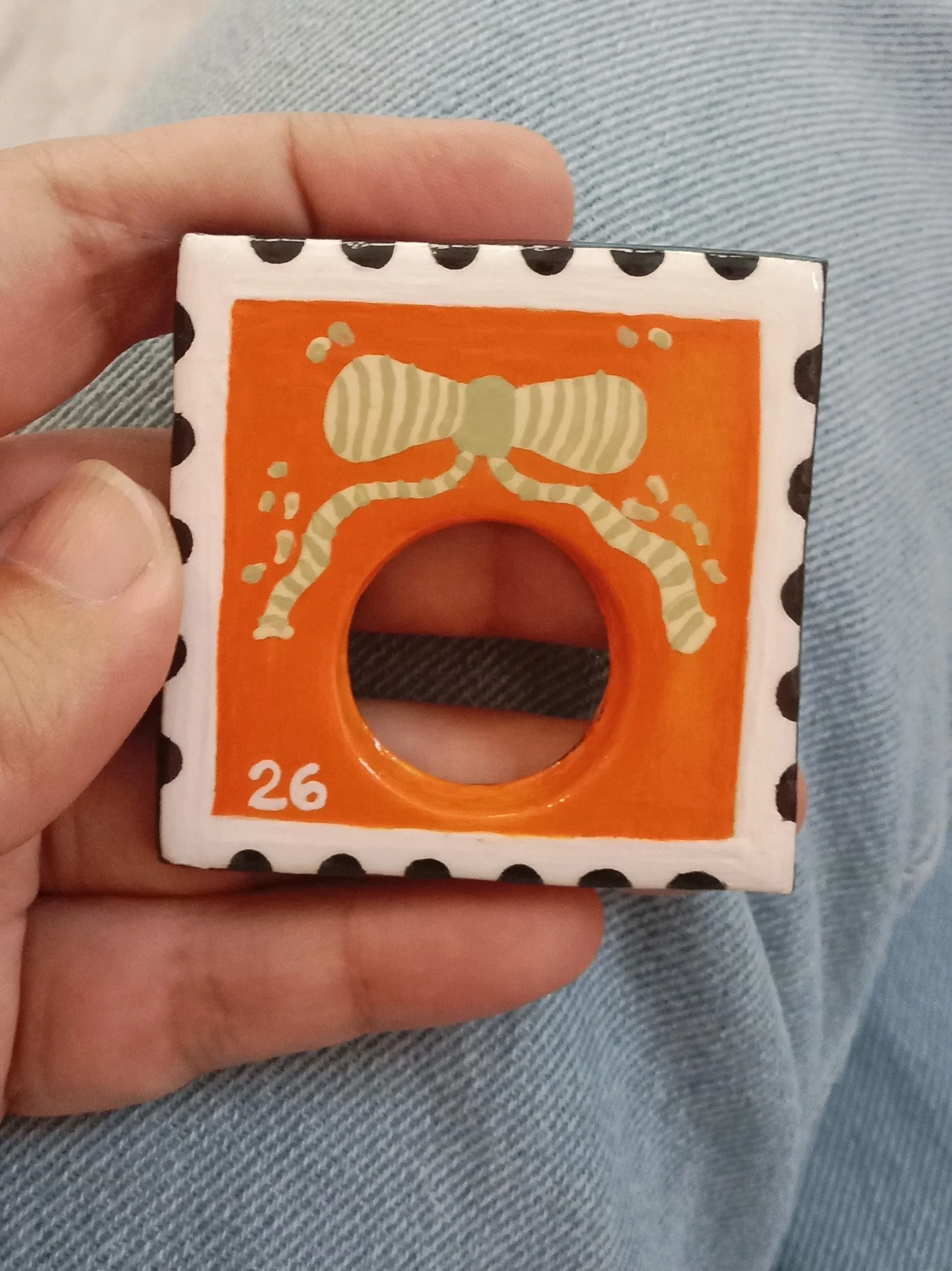 Close up of an orange clay postage stamp brooch