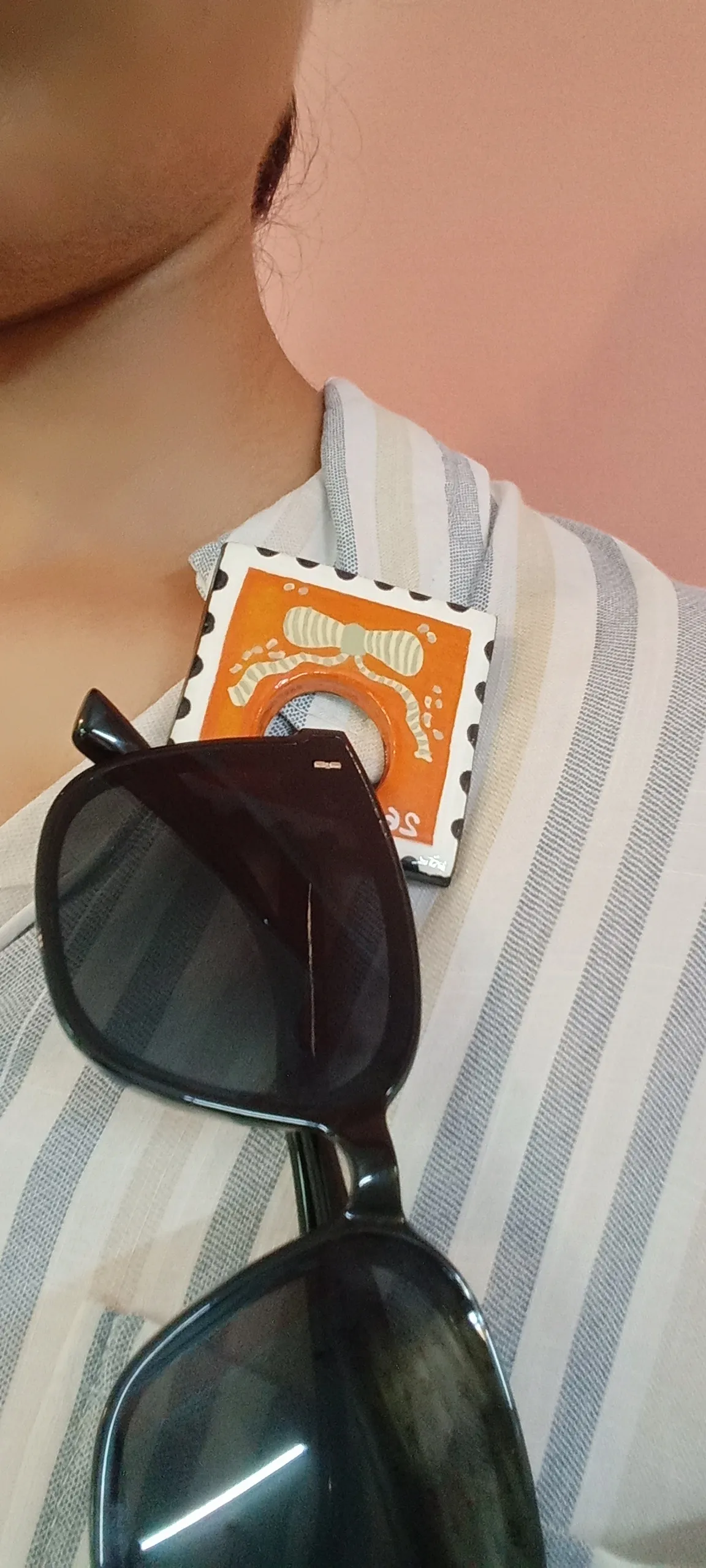 Brooch holding sun glasses pinned to a collar of a shirt