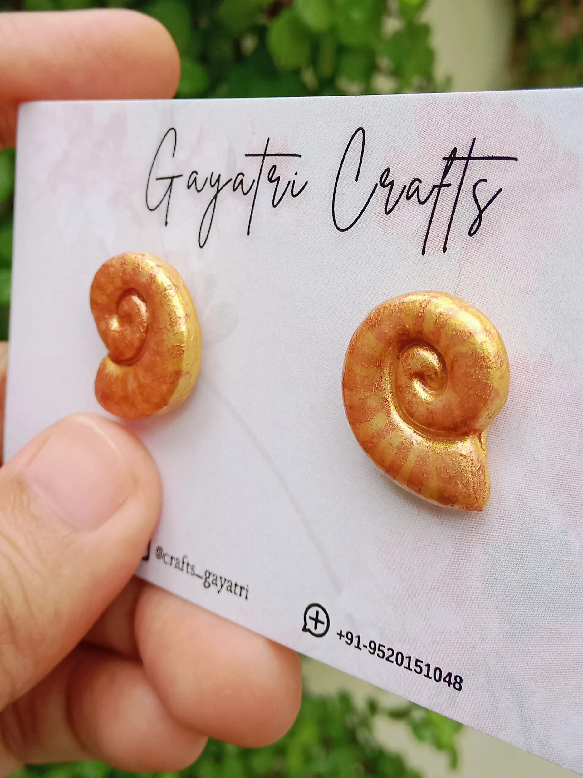 Another side view of Studio Gayatri handmade golden spiral shell clay stud earrings on a clean background