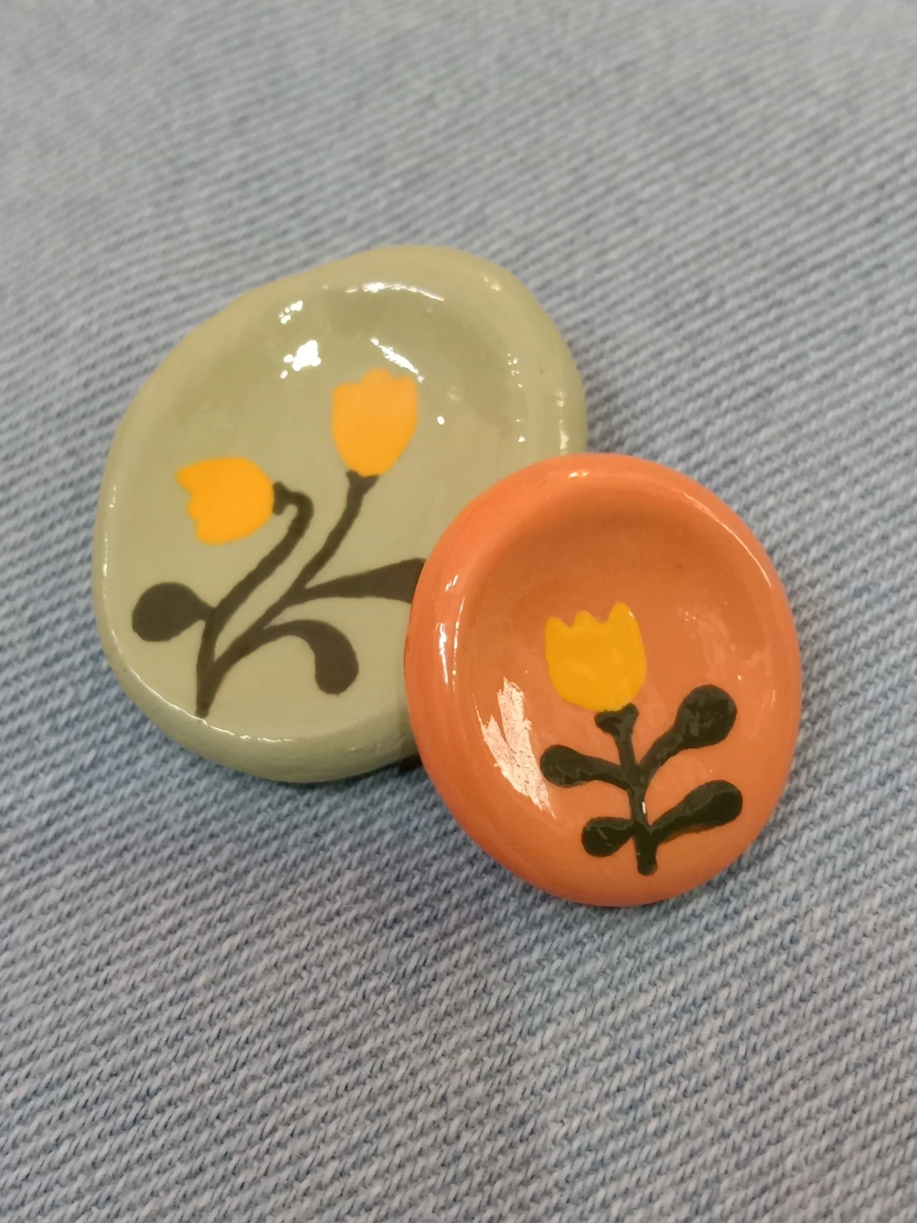 Studio Gayatri set of two handmade boho floral clay worry stones showing their smooth organic shapes on a denim backdrop.